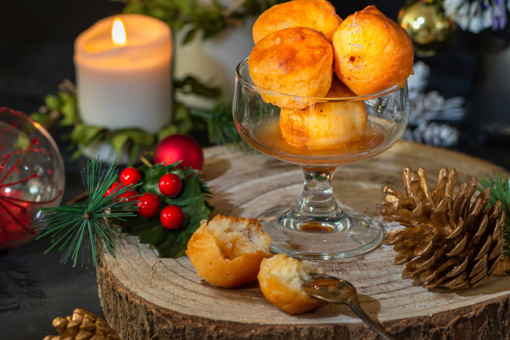 Festive Rum Babas in a glass bowl alongside red holly berries